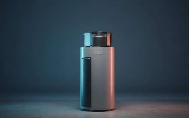 A freestanding heat pump water heater with a compressor and fan housing on top, standing alone on a concrete floor